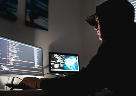 man in a hooded jacket at a computer